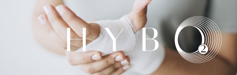 Womans hands held together with gauze bandage wrapped around palm and wrist covering burn on skin
